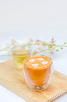 Glass hot thai tea cup with white foam surface and hot tea