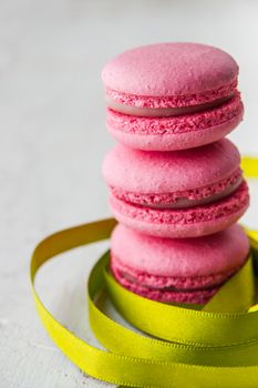 Pink macaroon on a white background with green ribbon vertical