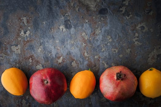 Lemons, pomegranates on the stone table horizontal