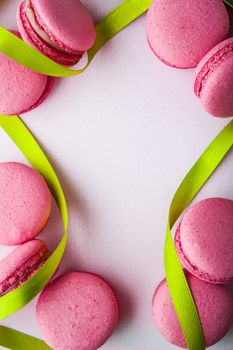 Pink macaroon on a white tablecloth with green ribbon vertical