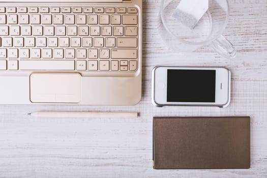 Laptop, mobile phone, notebook on a wooden table horizontal