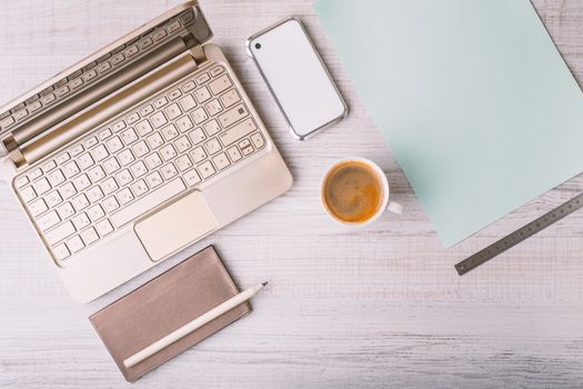 Laptop, phone and address book and a cup on a wooden table horizontal