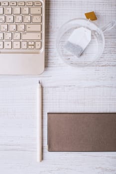 Laptop and notebook and a cup on a wooden table vertical