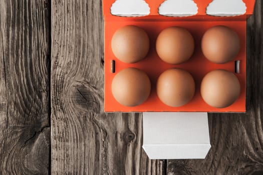 Chicken eggs in a paper box on a wooden table horizontal