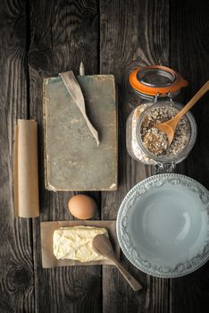 Recipe book, plate and ingredients for cookies on a wooden table vertical super still life