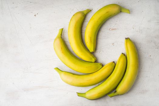 Yellow bananas are laid by a fan on a white table horizontal