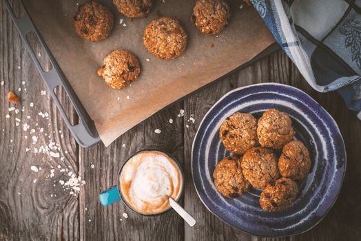 Baking tray and a plate of oatmeal cookies on the wooden table horizontal