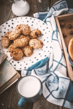 Book, pitcher, oatmeal cookies and a cup of milk on old boards vertical