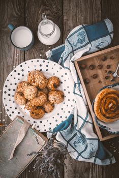 Book, lavender, oatmeal cookies and a cup of milk on old boards vertical