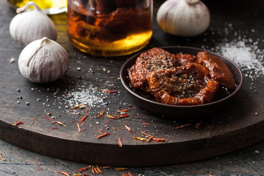 Sun-dried tomatoes on the ceramic plate on the wooden board horizontal