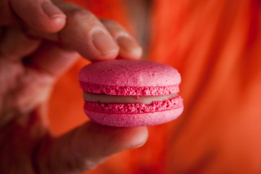 Woman holds in her hand macaroon horizontal