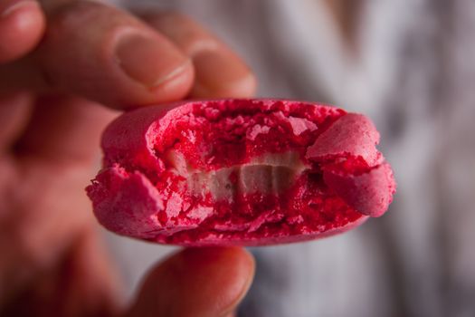 A woman holds  bitten off macaroon in her hand horizontal