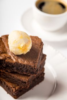 Brownie with ice cream and a cup of coffee on the table vertical