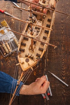 Man collects the vehicle model on the wooden table vertical