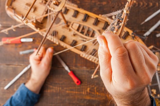 Man collects the vehicle model on the wooden table horizontal