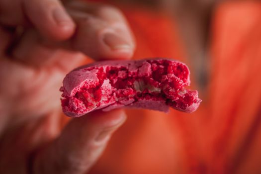 Woman holds  a broken macaroon in her hand  horizontal