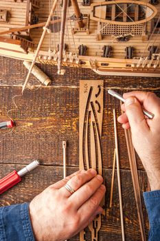 Man collects the vehicle model on the wooden table vertical