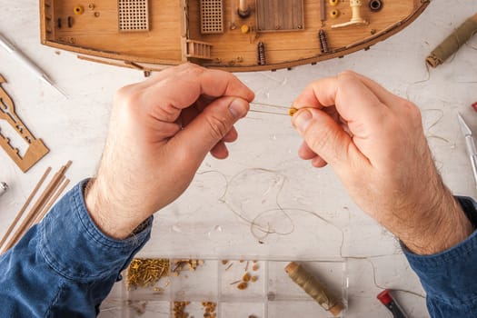 Man collects ship model on a white table horizontal