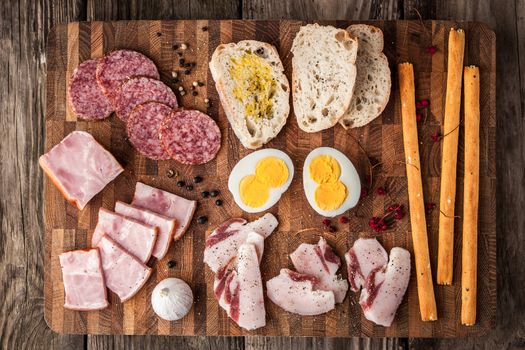 Eggs, ham, sausage, bread, pepper, garlic on a cutting board horizontal