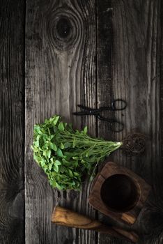 Basil, scissors and mortar on old boards vertical