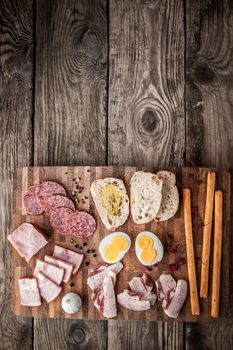 Eggs, ham, sausage, bread, pepper, garlic on a cutting board vertical