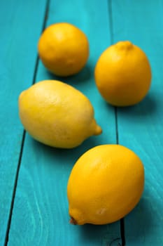 Yellow colorful lemons on the bright cyan wooden table vertical