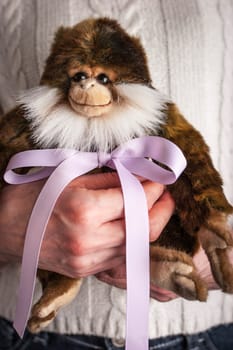 Monkey toy  with violet ribbon in the woman hands