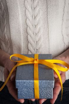 Blue present with yellow ribbon in the hands vertical
