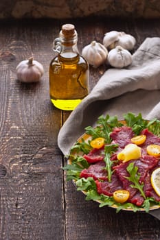 Carpaccio with arugula, tomatoes and cheese on the rustic table