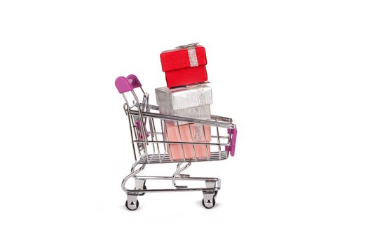 Side view of shopping card or trolley with colorful gift boxes isolated on white background.