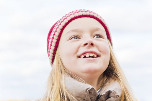Portrait of cute smiling girl in red hat in autumn