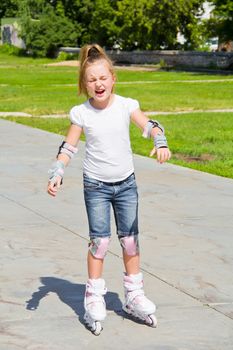 Learning girl on roller skates in summer