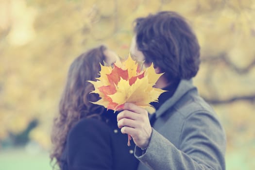 Happy couple kissing in autumn park with yellow trees