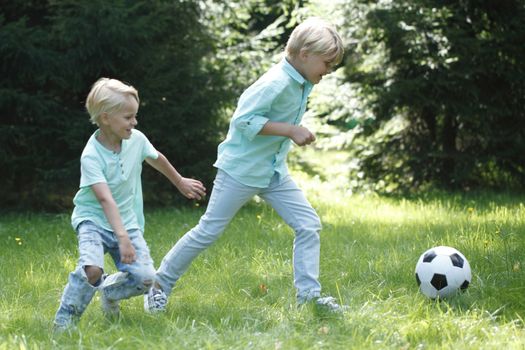 Happy children playing football in summer park