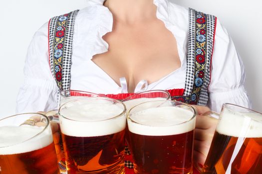 Young sexy woman wearing a dirndl with beer mugs over white, Oktoberfest concept