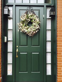 Green door with floral wreath, outside.
