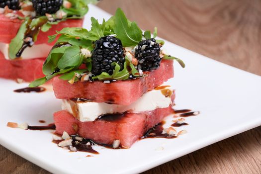 appetizer  stacked slices of watermelon, feta, arugula, blackberry sauce and nuts
