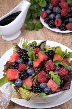 Fruit salad with blackberry, raspberry, blueberry, watermelon slices and mix of green leaves