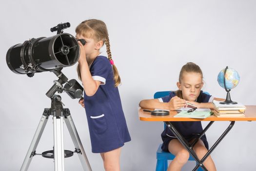 Girl watching the celestial bodies in the telescope, the other girl is waiting for the results of observations