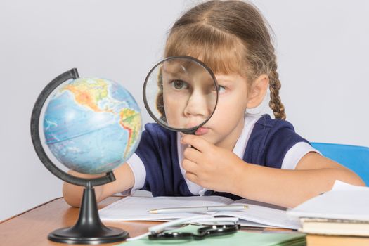 Schoolgirl looking at globe through a magnifying glass