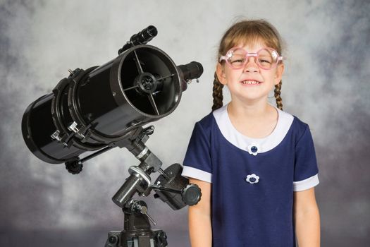 Girl bespectacled amateur astronomer funny smiling standing by telescope