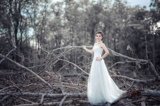 Beautiful girl in the dress of the bride walks in autumn park with trees and fallen leaves