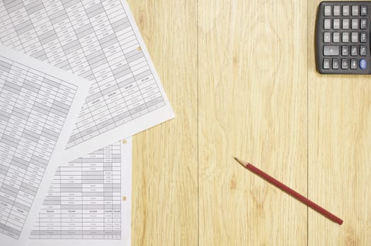 Brown pencil and paperwork of finance account with calculator place on wood background.