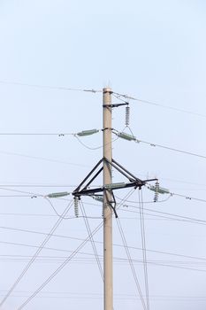 photographed electric poles located in the field during the day against the blue sky, industrial buildings