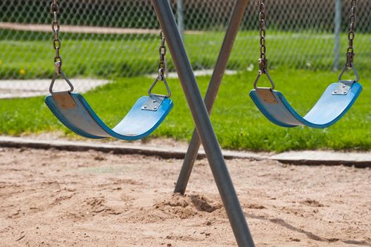 Swings at the city park sitting idle without the joy and laughter of playing children.