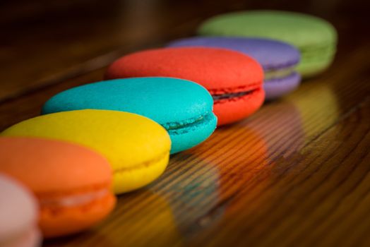 Image of a row of colorful macaroons on wooden table