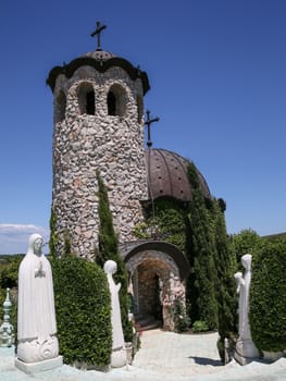 Small church with sculptures under nice sky.