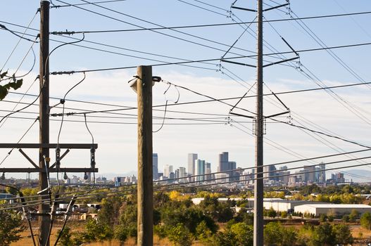 Cluttered power poles and lines in front of view of downtown Denver, Colorado, USA.