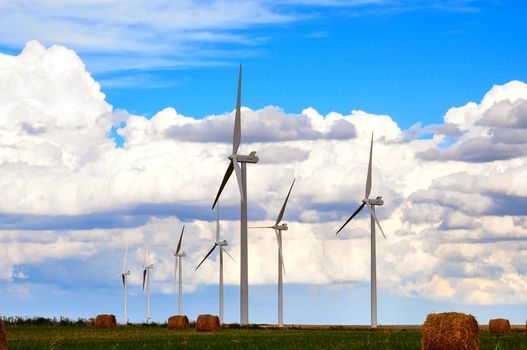 Wind generators standing in farmland under beautiful prairie skies.