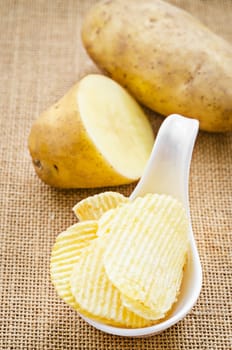 chips and peeled potatos on a sack background.